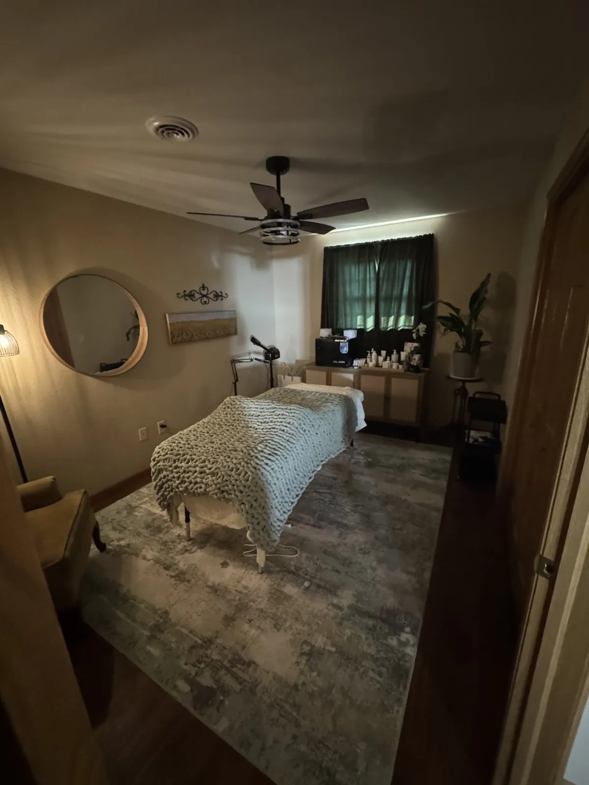 Softly lit treatment room with a massage table draped in a knit blanket